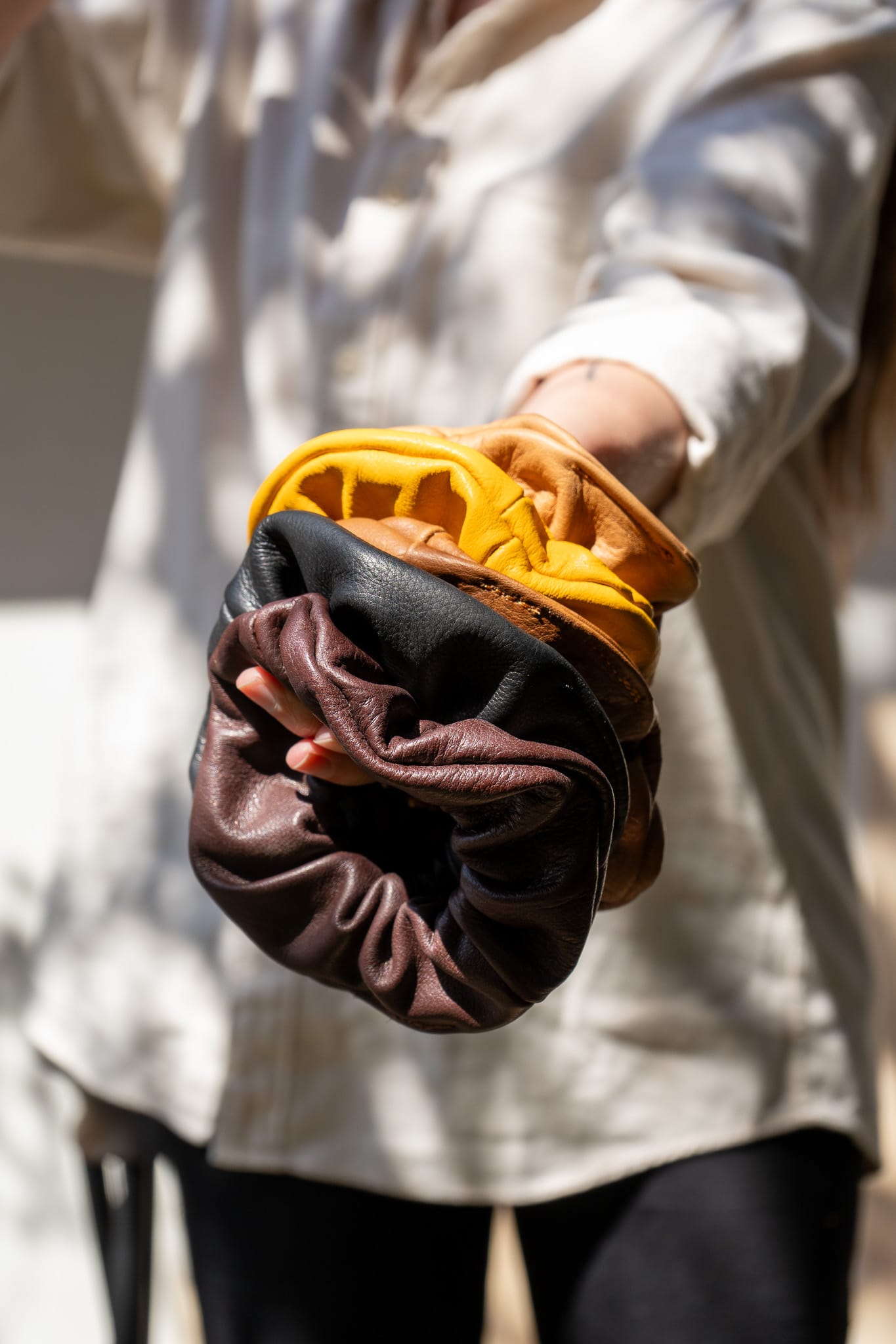 A person's hand wearing a brown leather scrunchie.