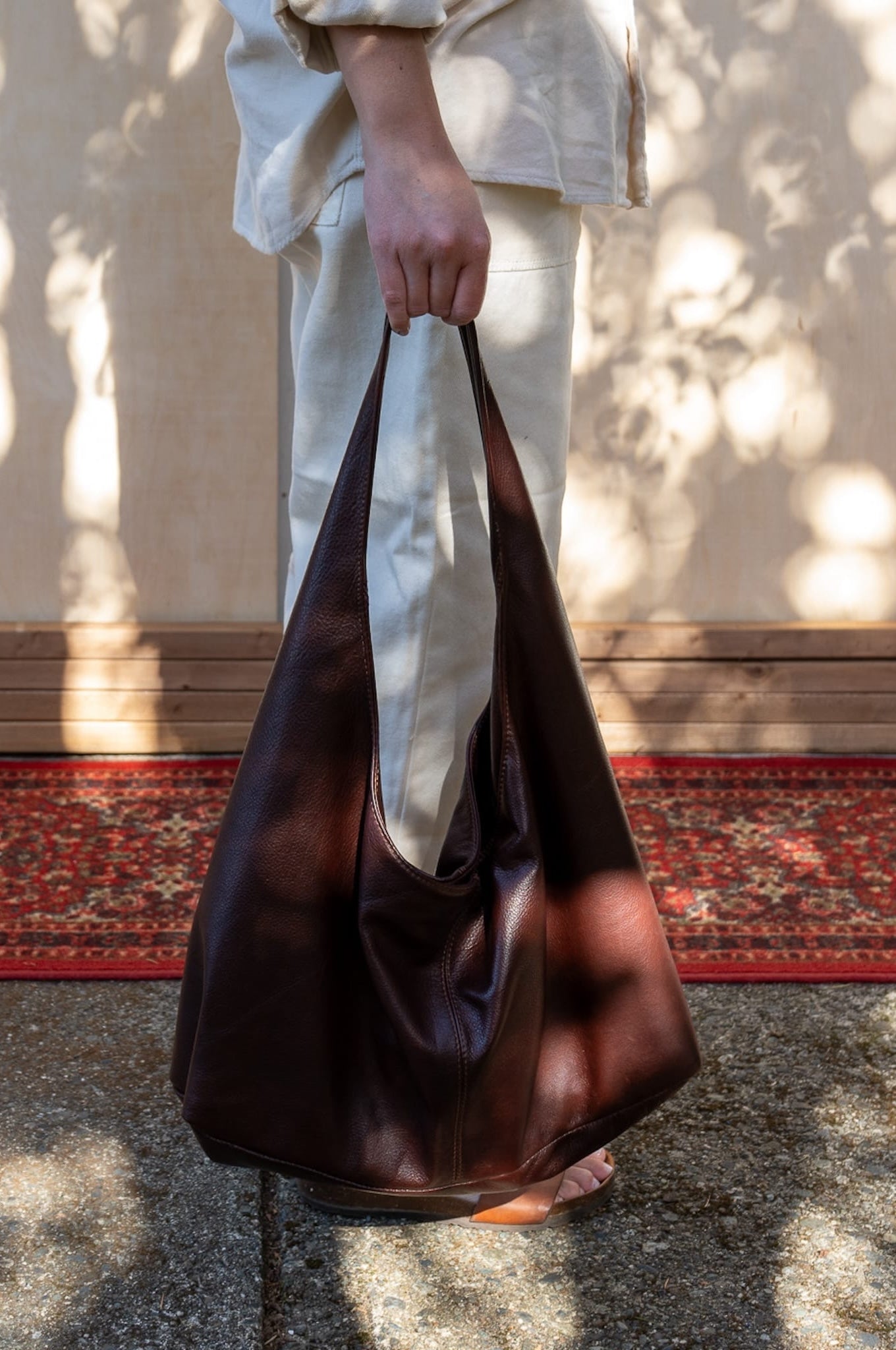 a person in a white outfit carrying a brown tote bag in their hand