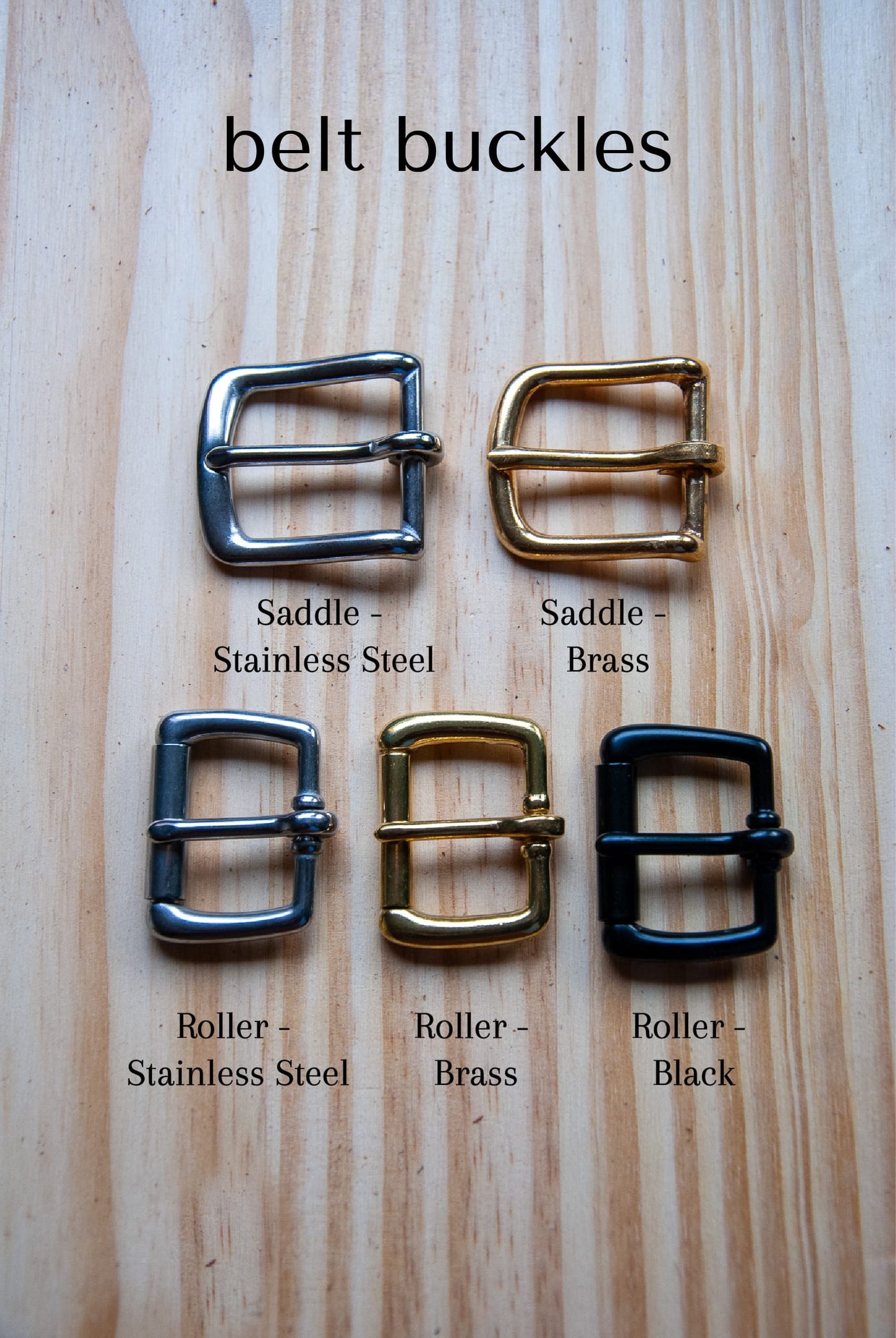 Set of belt buckles labeled with material and color on a wooden surface