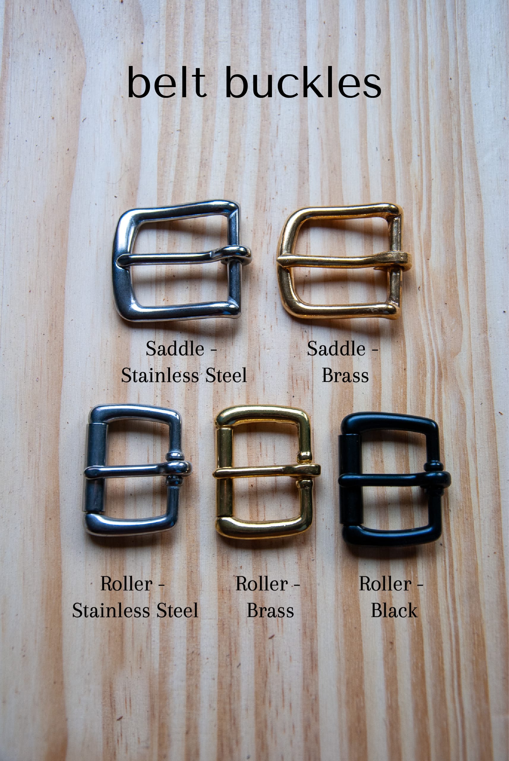 Set of belt buckles labeled with material and color on a wooden surface