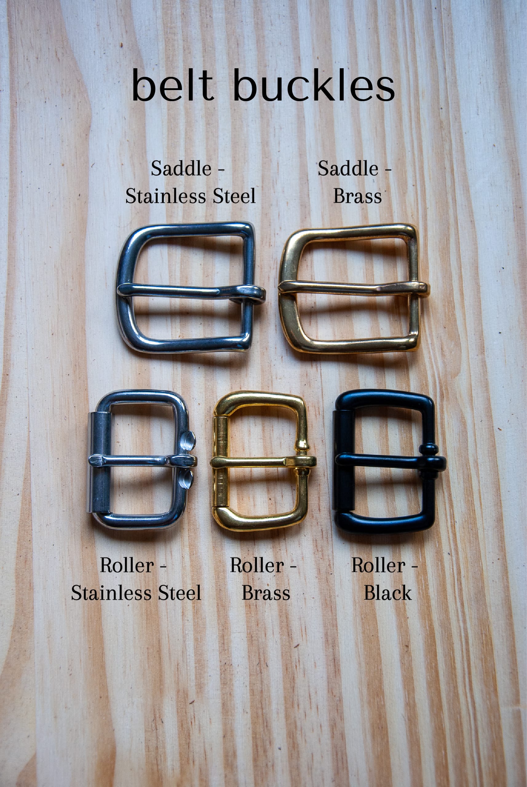 Set of belt buckles labeled with material and color on a wooden surface