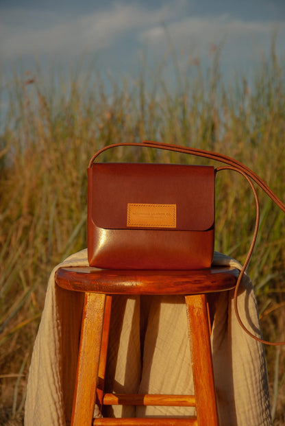 Brown leather bag on a wooden stool with a natural background