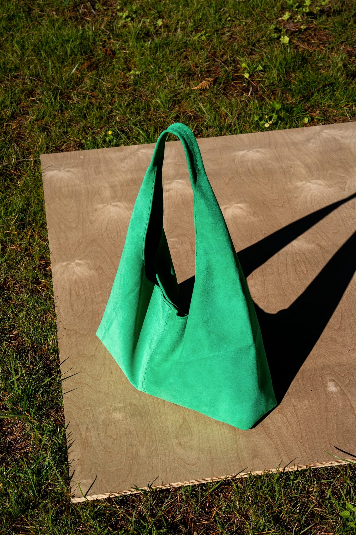 Green handbag on a wooden board outdoors