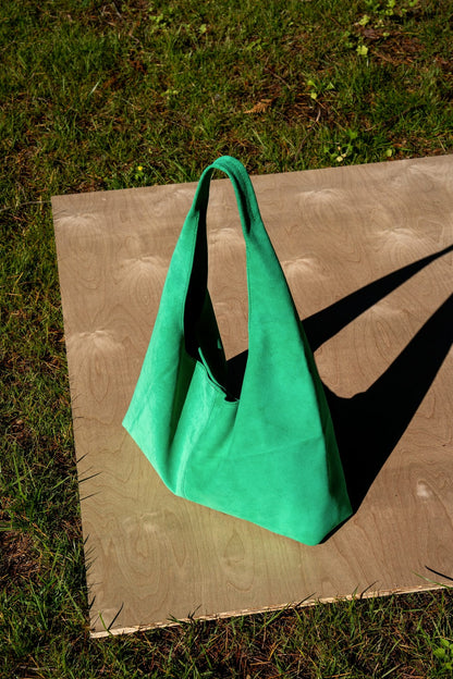 Green handbag on a wooden board outdoors