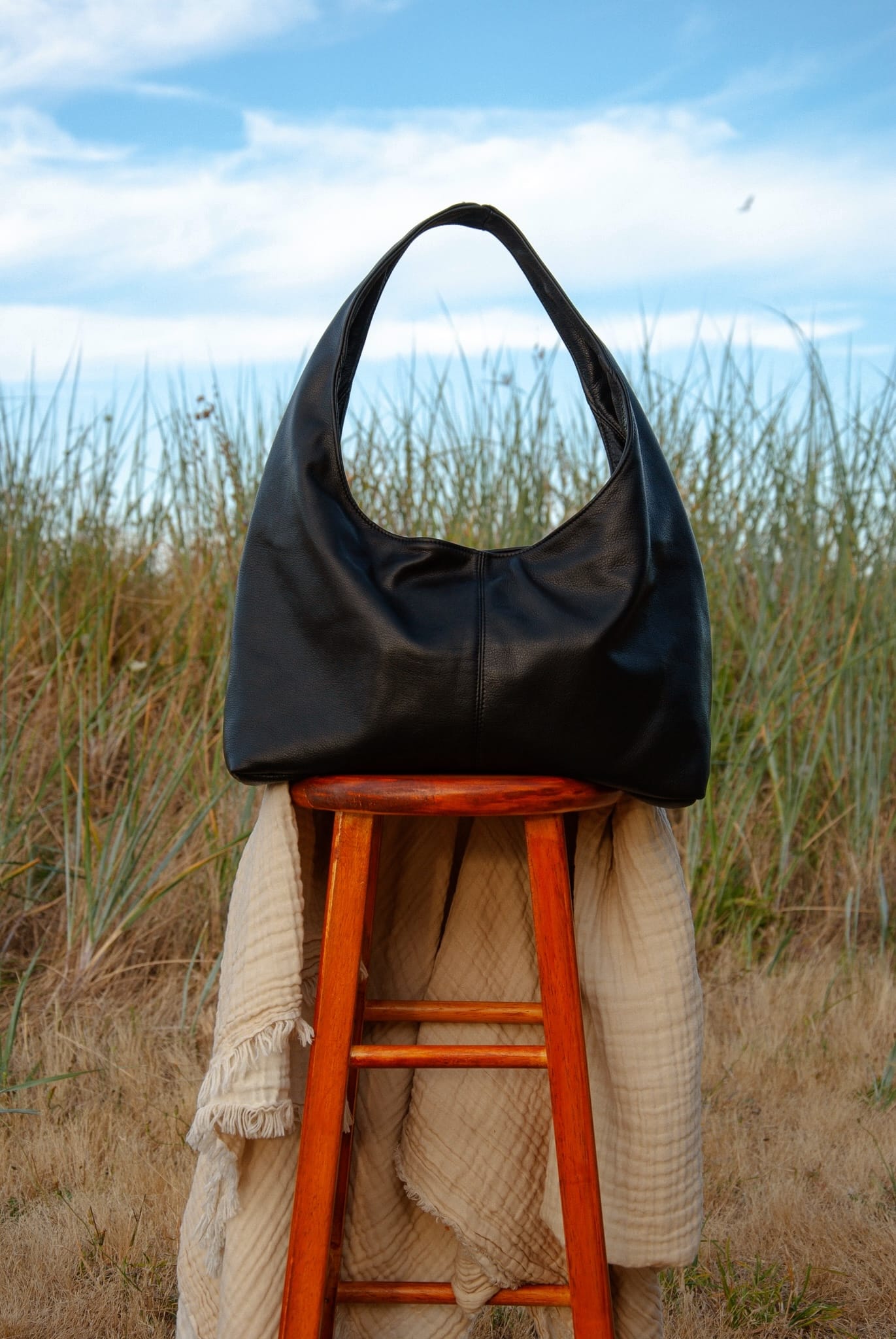 Black handbag on a wooden stool with a natural background