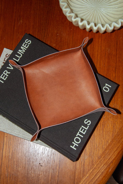 Brown leather tray on top of a book titled 'Hotels'.