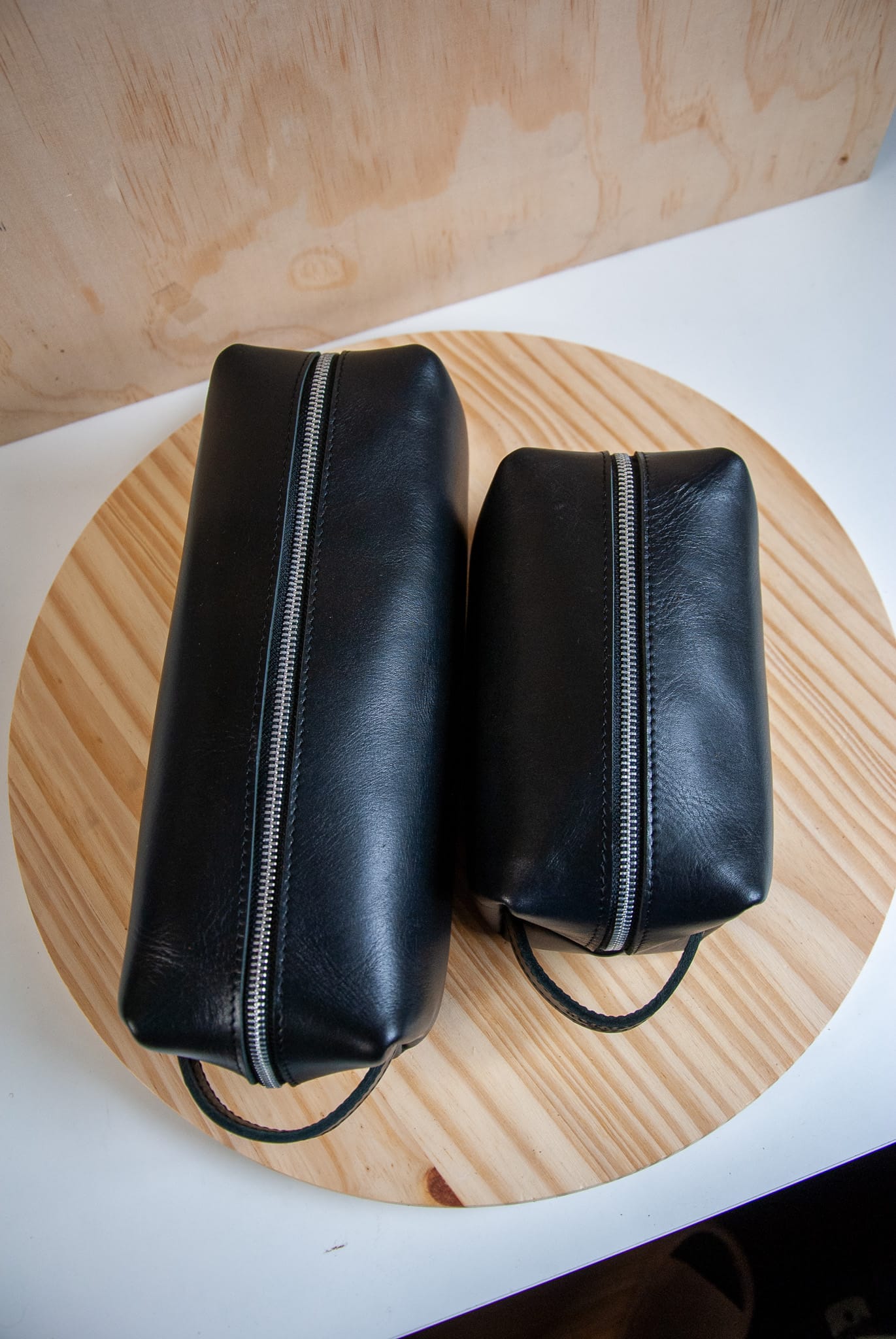 Two black leather pouches on a wooden surface