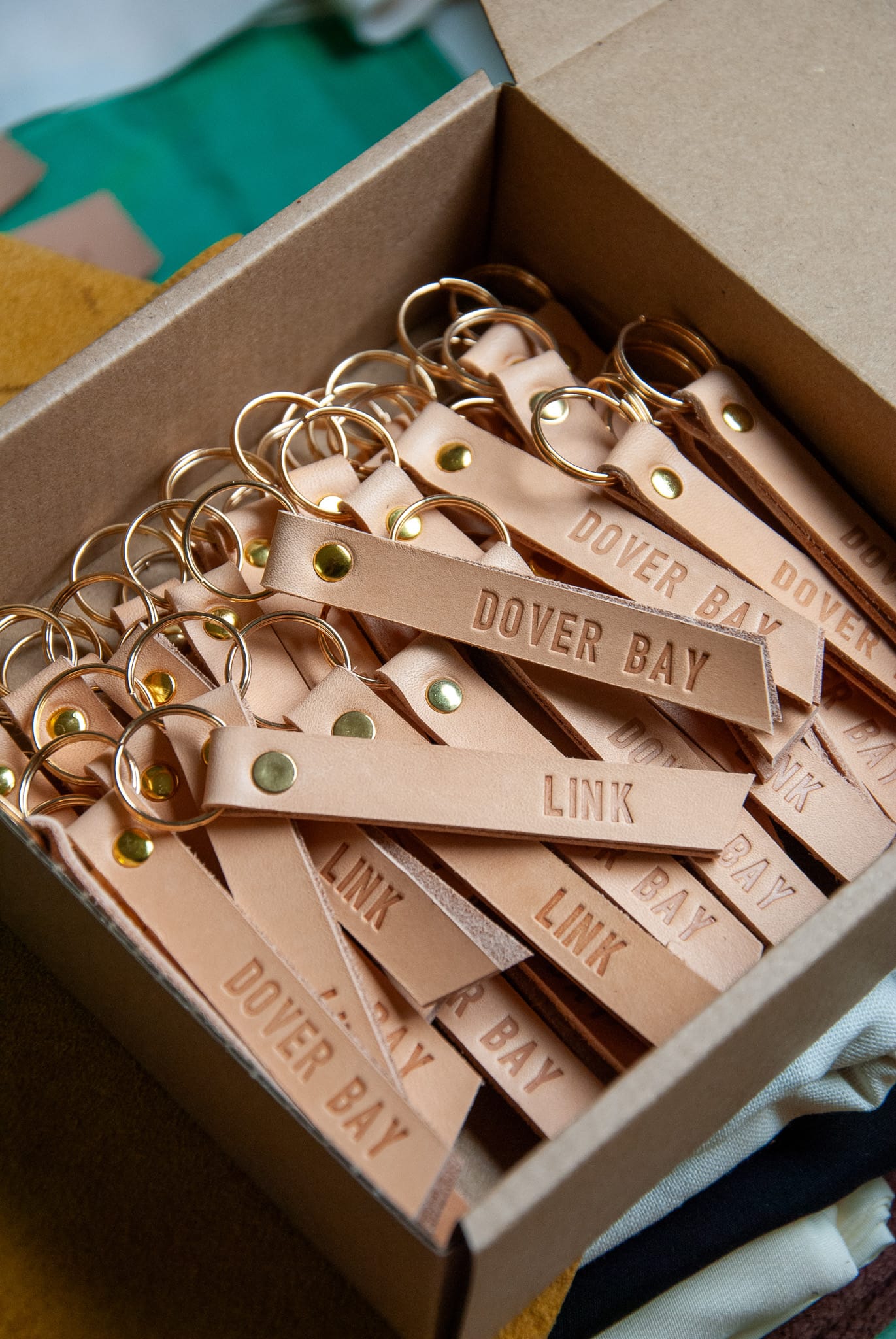 Box of leather keychains with 'Dover Bay' branding.