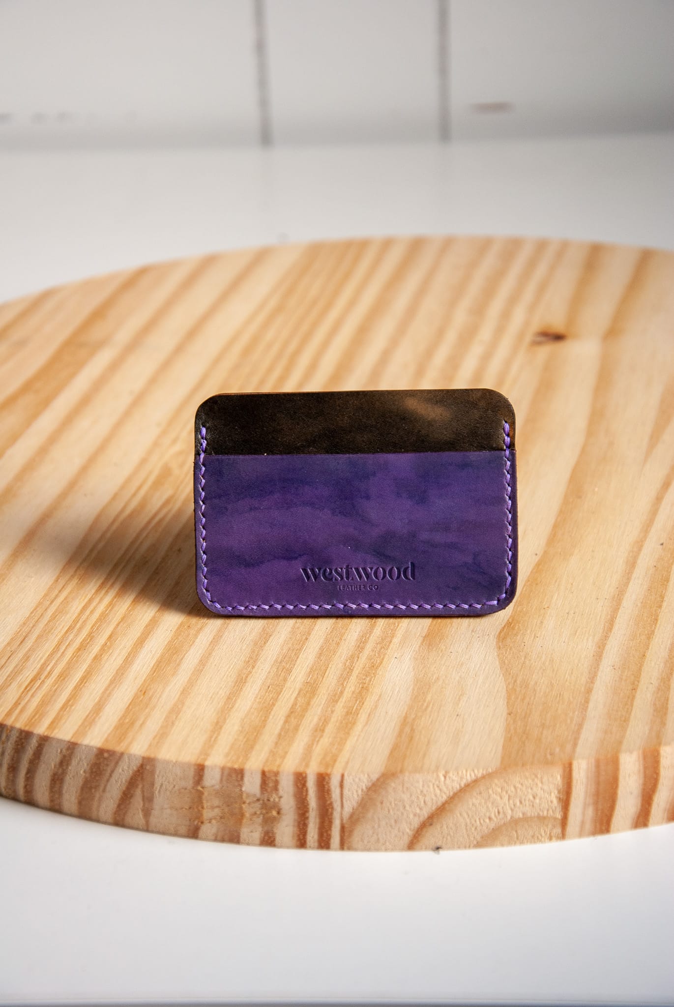 Purple wallet with 'Westwood' branding on a wooden surface
