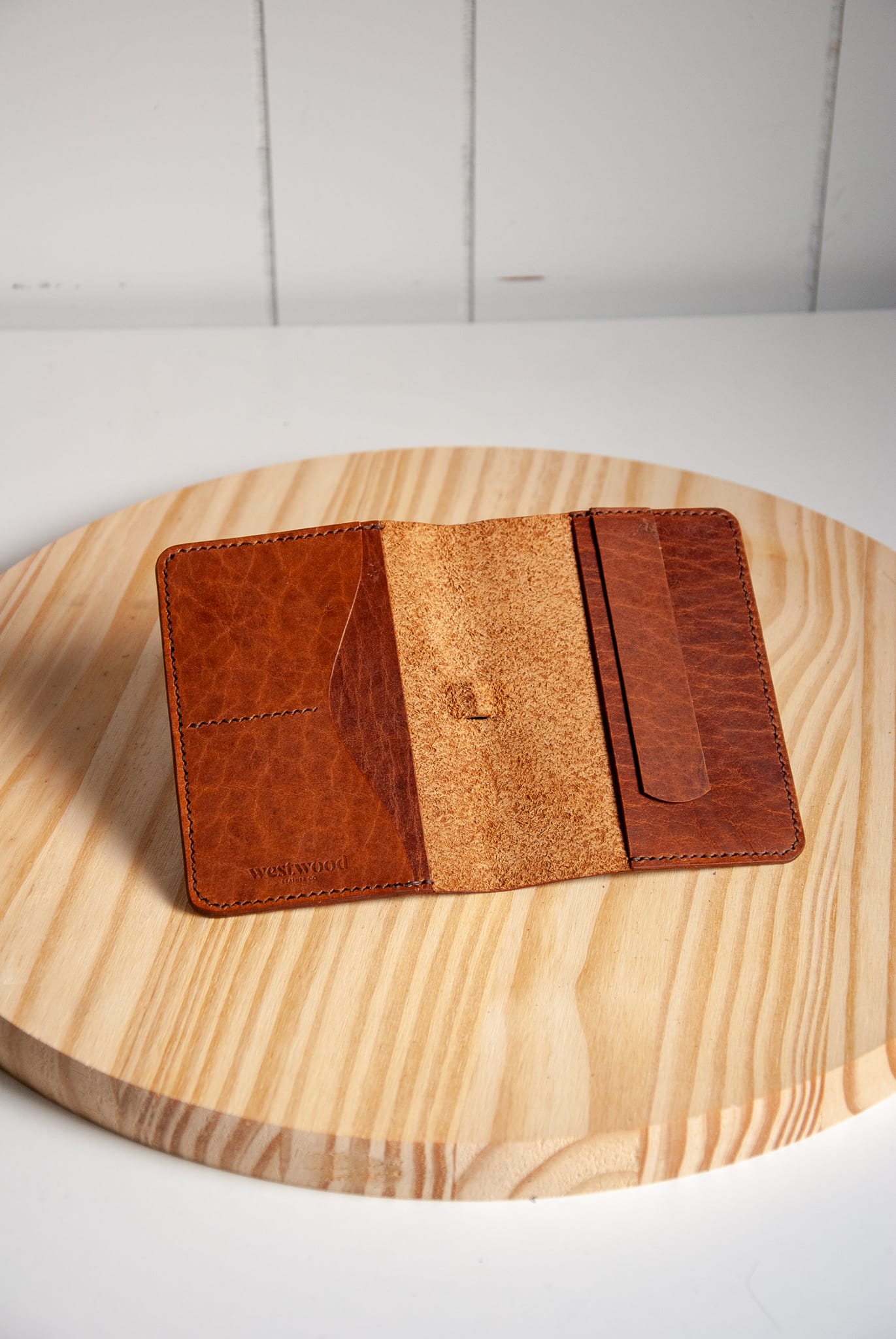 Brown leather wallet on a wooden surface with a white background