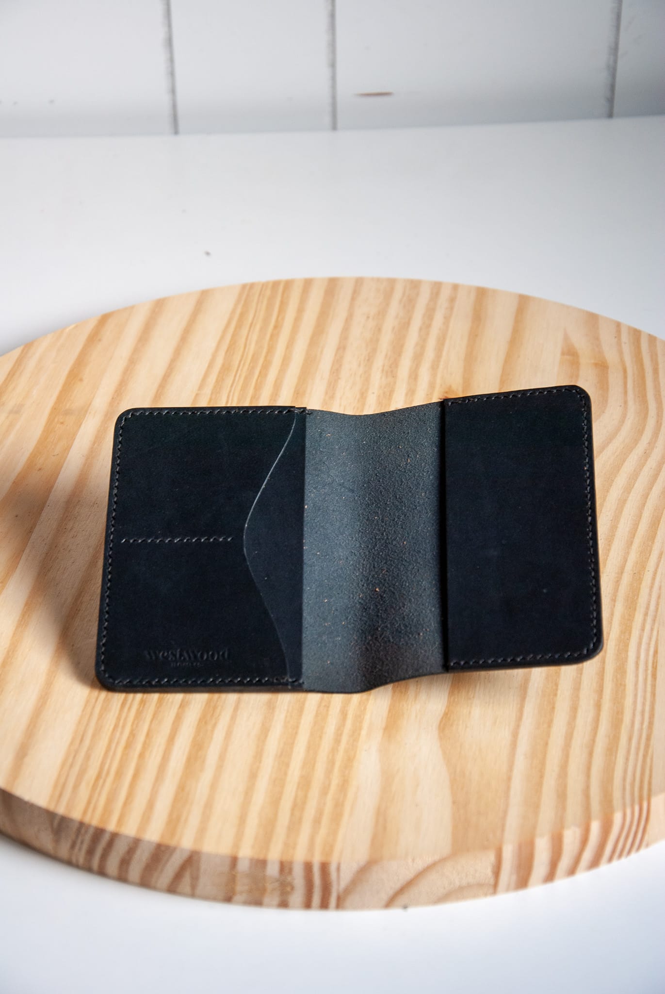 Black leather wallet on a wooden surface with a white background