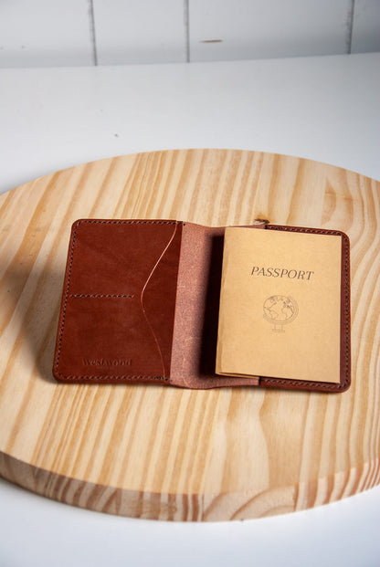 Brown leather passport holder with a passport on a wooden surface