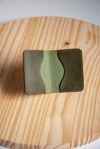 Two-tone green leather wallet on a wooden surface