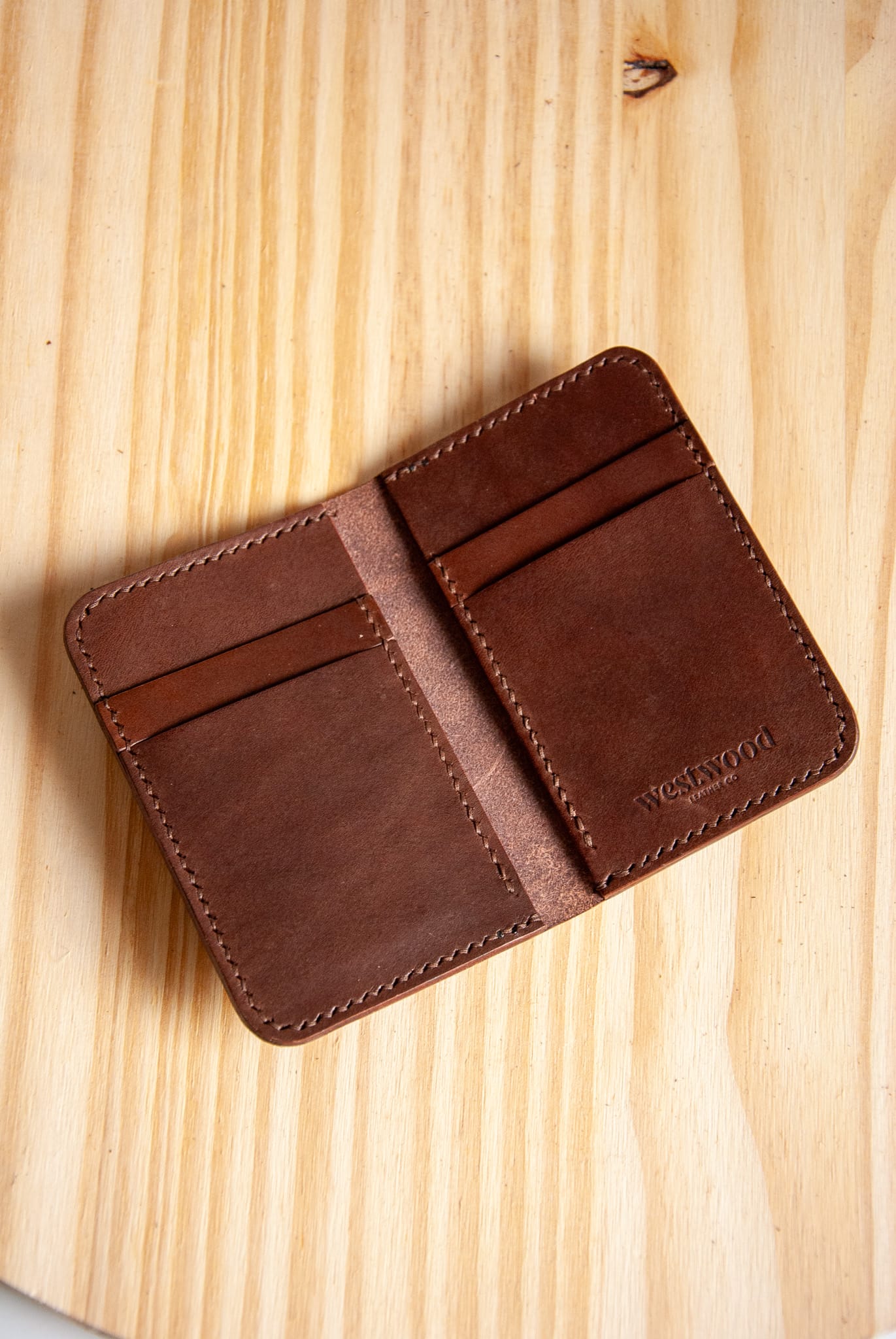 Brown leather wallet on a light wood surface