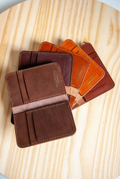 Five leather wallets in brown and orange on a wooden surface